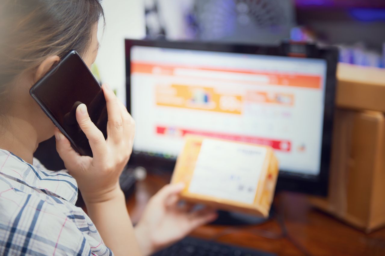 The Art of Drawing Readers In: Your attractive post title goes here Woman multitasking by using a phone and checking an online purchase package at home.